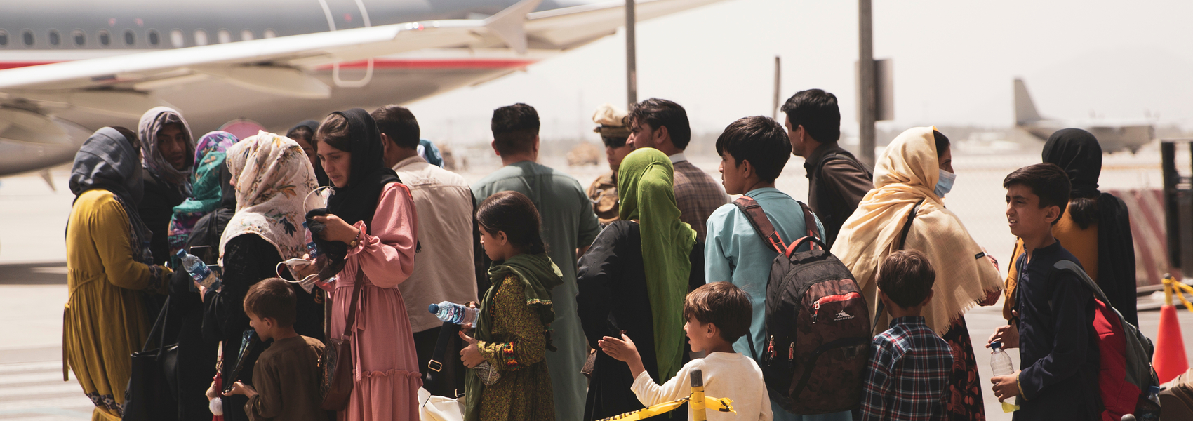 Crowd of people waiting outside to board airplane in Afghanistan